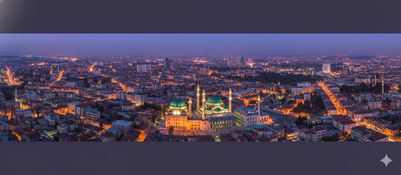 Konya'nın alacakaranlıktaki çok geniş panoramik havadan görünümü, ön planda belirgin yeşil kubbeleri ve minareleri ile aydınlatılmış Selimiye Camii'ni öne çıkaran, berrak, mavi ve mor alacakaranlık gökyüzü altında yayılan şehir ışıkları ile çevrili.
